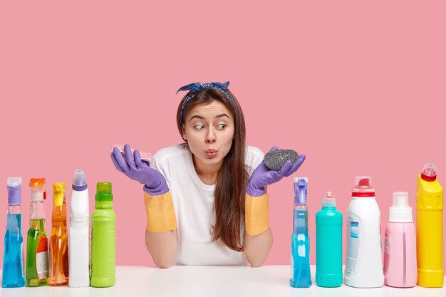 Giovane donna bruna seduta accanto a prodotti per la pulizia
