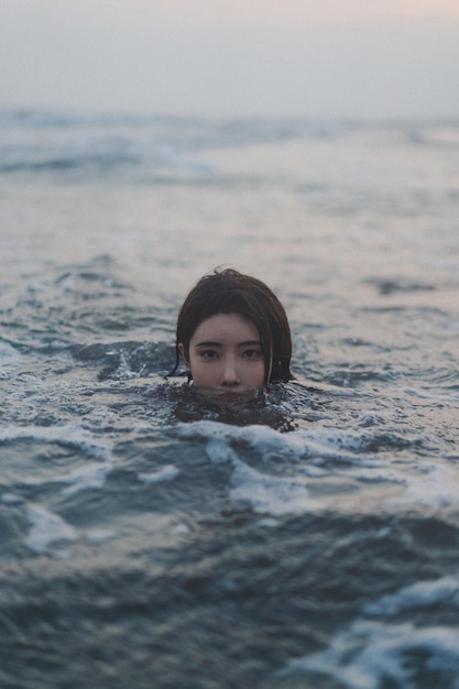 Giovane donna bruna sudcoreana che nuota nel mare al mattino