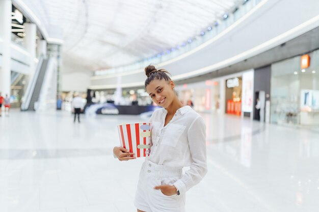 Giovane donna carina che tiene popcorn in background centro commerciale