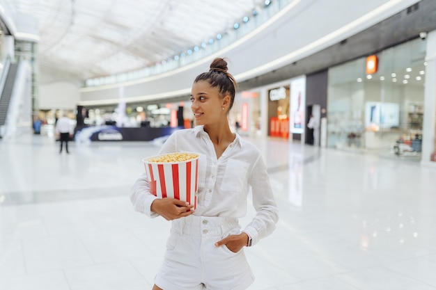 Giovane donna carina che tiene popcorn nel centro commerciale