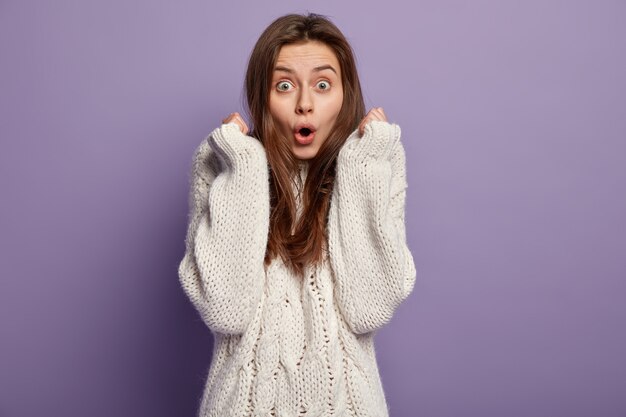 Giovane donna castana che indossa un maglione bianco