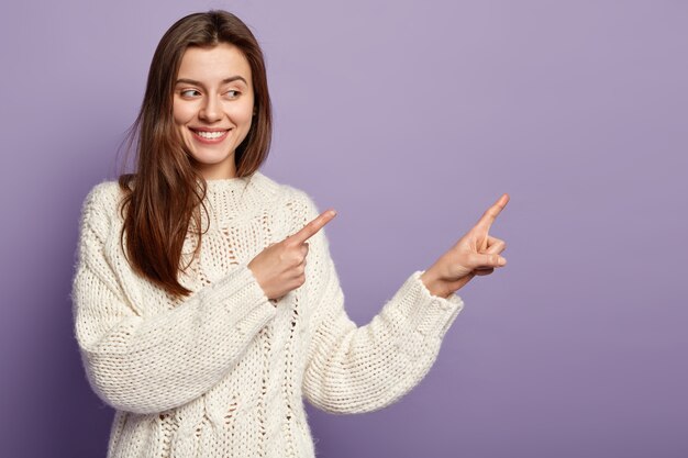 Giovane donna castana che indossa un maglione bianco