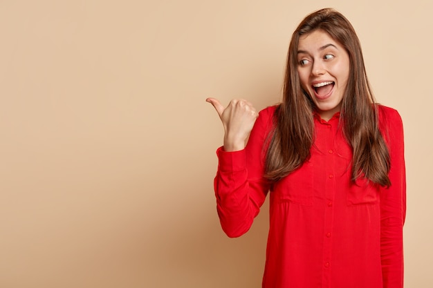 Giovane donna castana che porta camicia rossa