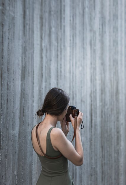 Giovane donna castana che prende un tiro con la macchina fotografica