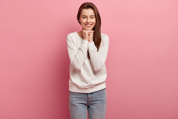 Giovane donna castana in jeans e maglione