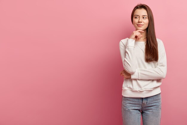 Giovane donna castana in jeans e maglione