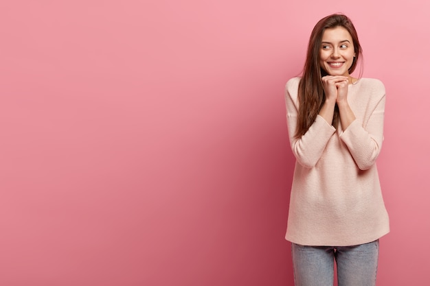 Giovane donna castana in jeans e maglione