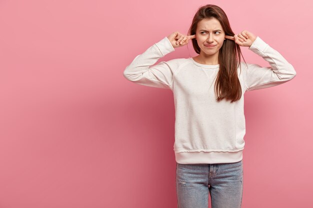 Giovane donna castana in jeans e maglione