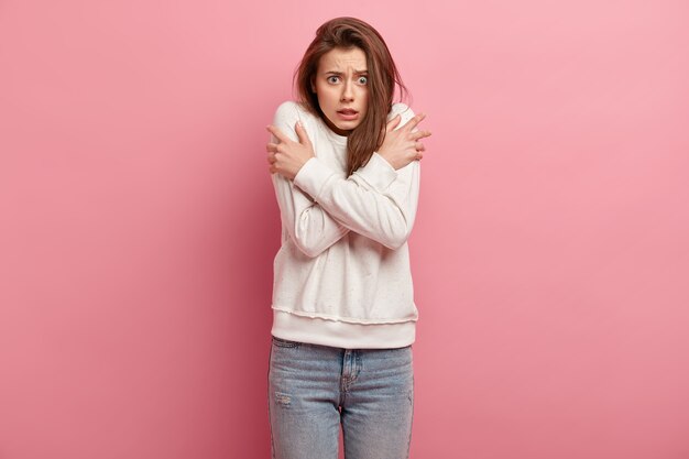 Giovane donna castana in jeans e maglione