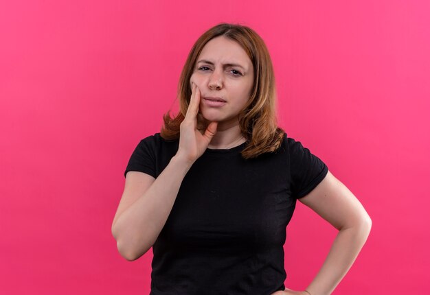 Giovane donna casual premurosa con le mani sulla guancia e sulla vita sulla parete rosa isolata con lo spazio della copia