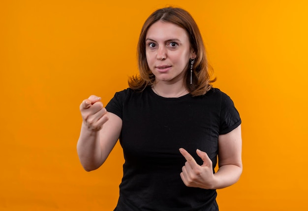 Giovane donna casuale impressionata che indica e se stessa sullo spazio arancione isolato con lo spazio della copia