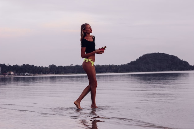 Giovane donna caucasica abbronzata adatta in mare al tramonto