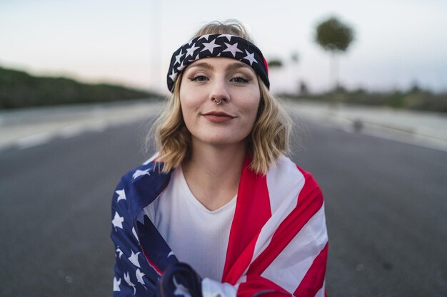 Giovane donna caucasica con la bandiera degli Stati Uniti sulle spalle