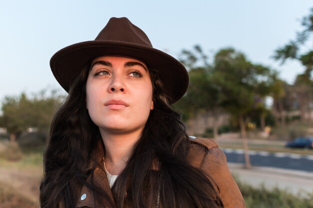 Giovane donna caucasica con un vestito da cowgirl in un parco naturale e guardando in lontananza