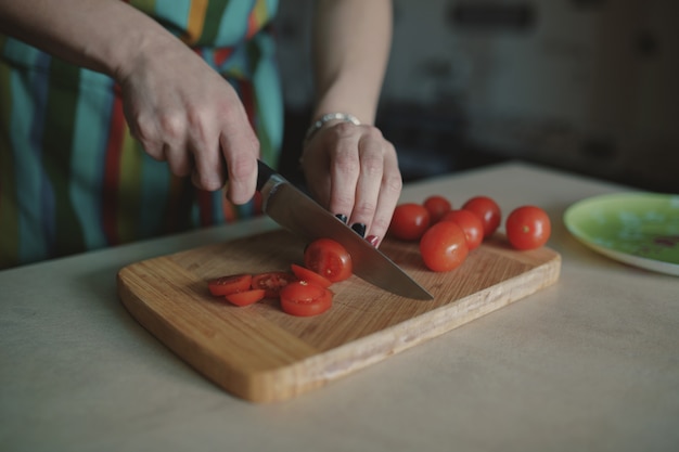 Giovane donna che affetta i pomodori