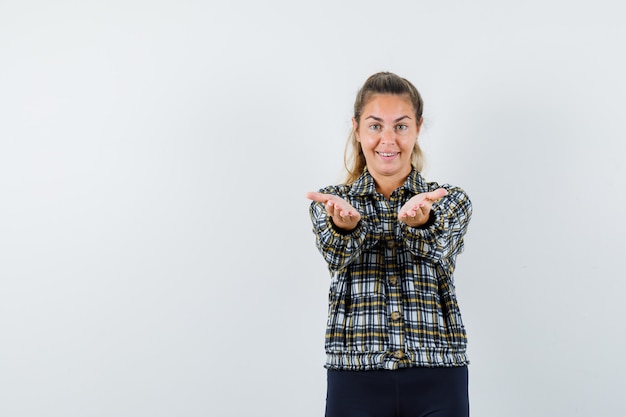 Giovane donna che allunga le braccia in camicia, pantaloncini e sembra allegra vista frontale.