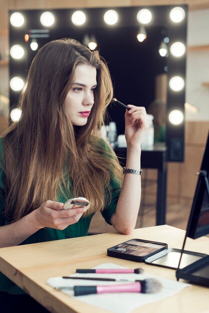 Giovane donna che applica trucco in studio