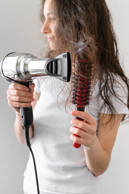 Giovane donna che asciuga i capelli