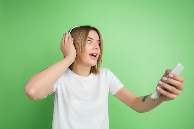 Giovane donna che ascolta la musica isolata sulla parete verde dello studio