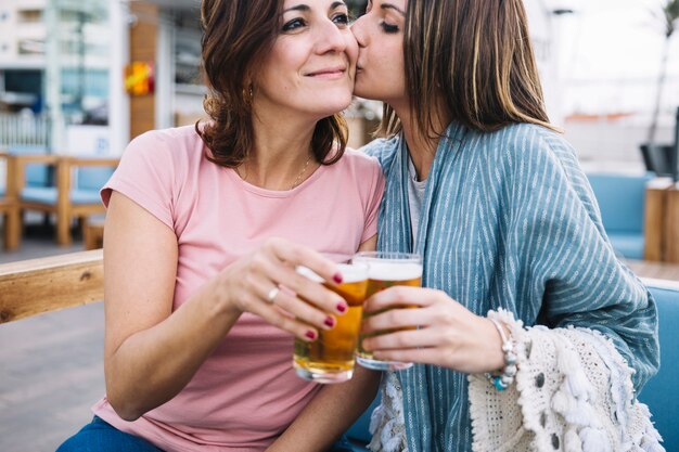 Giovane donna che bacia la donna mentre aderendo occhiali