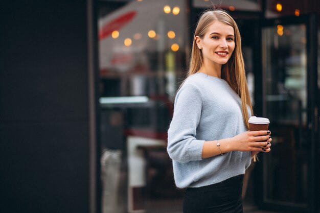 Giovane donna che beve caffè al bar