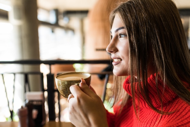 Giovane donna che beve caffè al mattino al ristorante