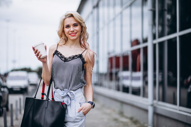 Giovane donna che beve caffè fuori dalla strada