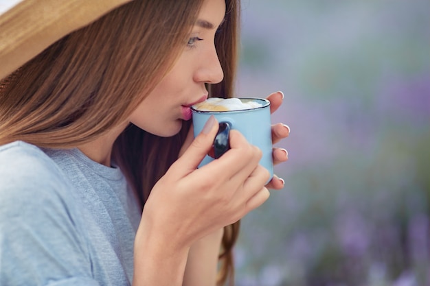 Giovane donna che beve caffè nel campo di lavanda