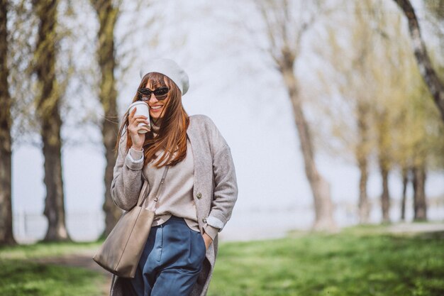 Giovane donna che beve caffè nel parco