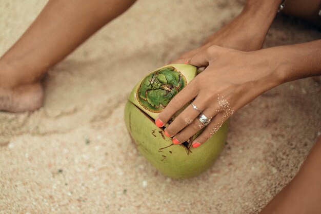 giovane donna che beve cocco tropicale sulla spiaggia