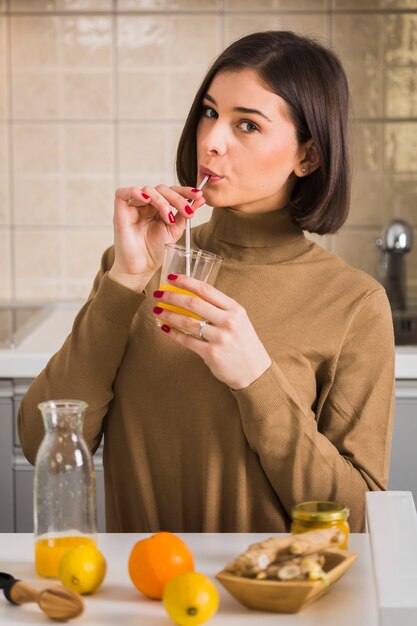 Giovane donna che beve il succo di arancia casalingo