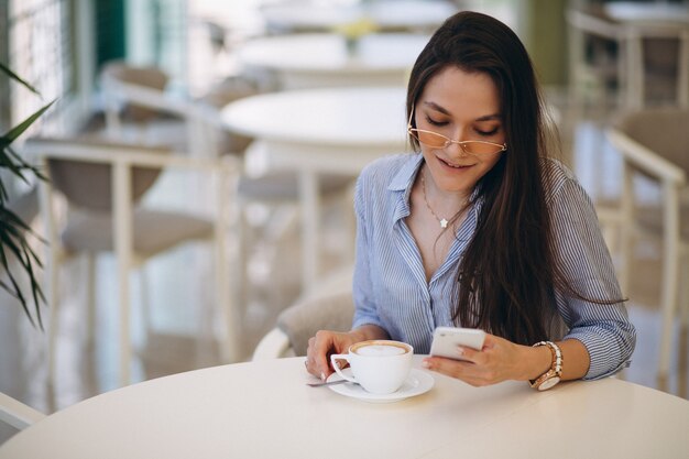 Giovane donna che beve il tè in un caffè