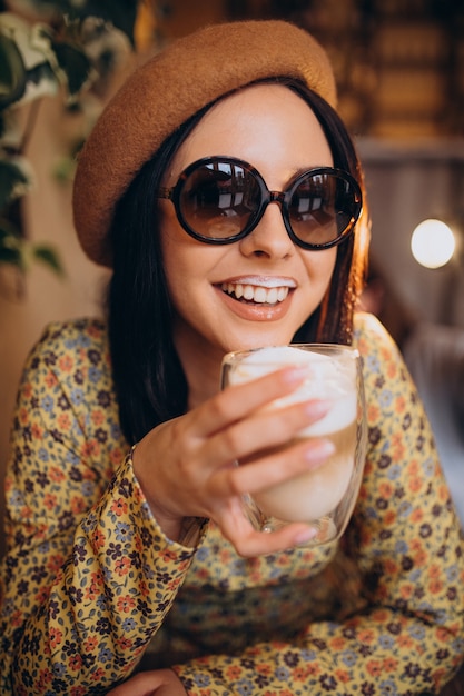 Giovane donna che beve latte in un caffè
