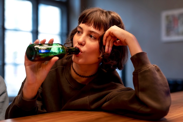 Giovane donna che beve una birra da sola