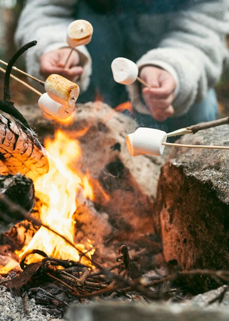 Giovane donna che brucia marshmallow nel fuoco di campo