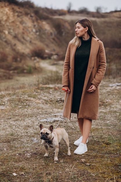 Giovane donna che cammina con l'animale domestico del bulldog in parco