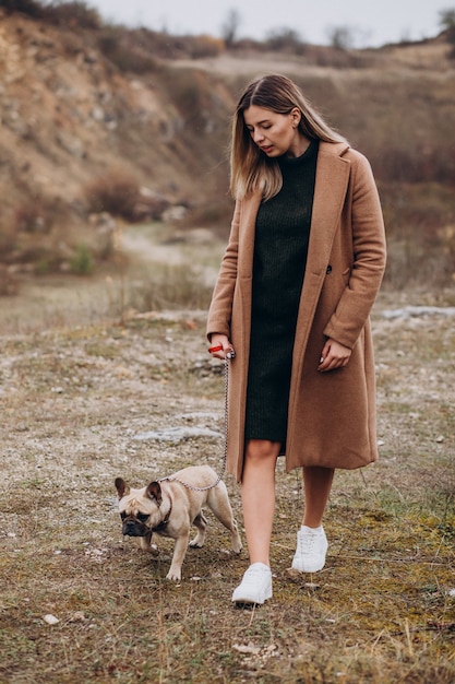 Giovane donna che cammina con l'animale domestico del bulldog in parco