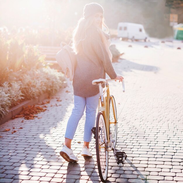 Giovane donna che cammina con la bicicletta