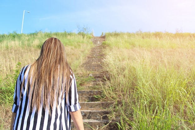 Giovane donna che cammina in campo verso il sole