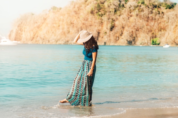 Giovane donna che cammina lungo la spiaggia vuota