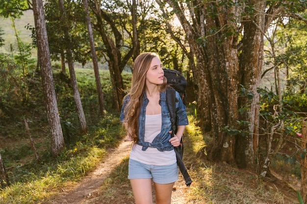 Giovane donna che cammina sulla strada non asfaltata nella foresta