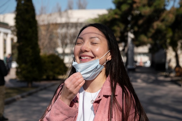Giovane donna che celebra la revoca delle restrizioni della maschera facciale all'aperto in città