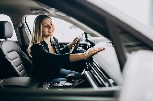 Giovane donna che collauda un'automobile in una sala d'esposizione dell'automobile