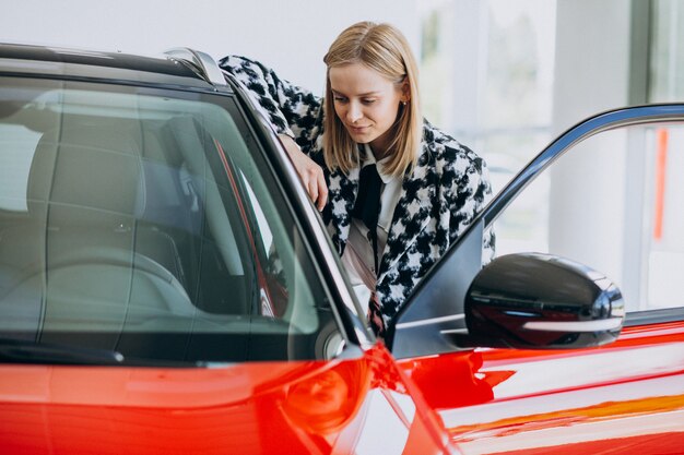 Giovane donna che compra un'automobile in una sala d'esposizione dell'automobile