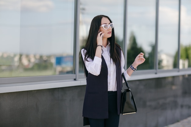 Giovane donna che comunica su un telefono con una borsa nera
