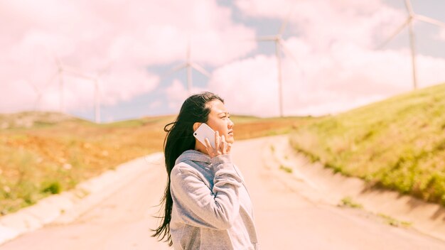 Giovane donna che comunica sul telefono sulla strada campestre