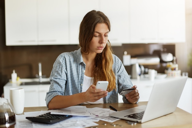 Giovane donna che controlla il suo bilancio e che fa le tasse