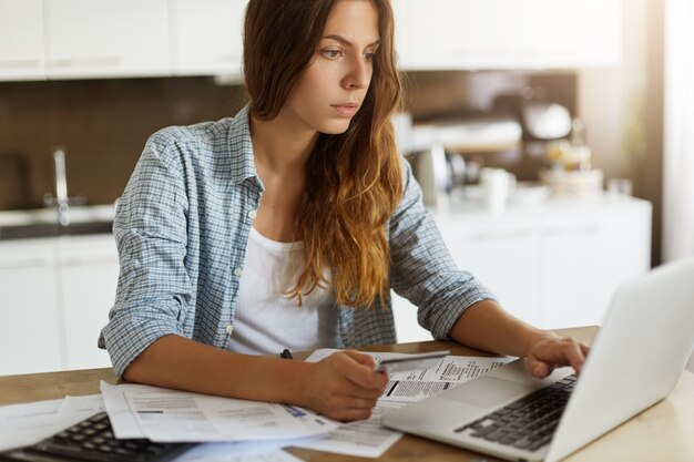 Giovane donna che controlla il suo bilancio e che fa le tasse