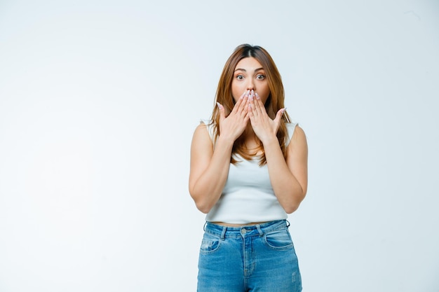 Giovane donna che copre la bocca con le mani e sembra stupita