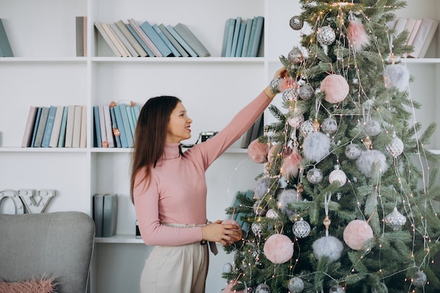 Giovane donna che decora l'albero di Natale